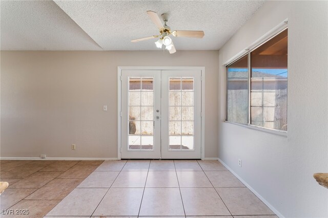 entryway with a textured ceiling, a wealth of natural light, light tile patterned floors, and french doors