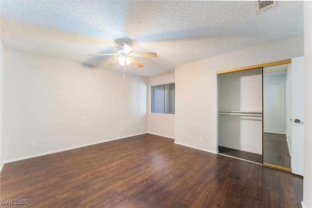 unfurnished bedroom with ceiling fan, dark hardwood / wood-style floors, a textured ceiling, and a closet