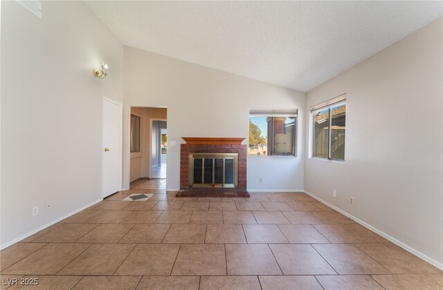 unfurnished living room with light tile patterned floors, vaulted ceiling, a brick fireplace, and a textured ceiling