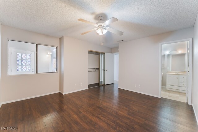 unfurnished bedroom featuring ensuite bathroom, ceiling fan, dark hardwood / wood-style floors, and a textured ceiling