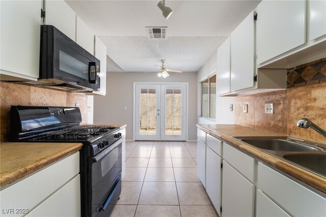 kitchen featuring light tile patterned floors, french doors, a textured ceiling, white cabinets, and black appliances