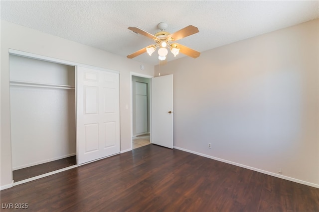 unfurnished bedroom featuring ceiling fan, a closet, dark wood-type flooring, and a textured ceiling