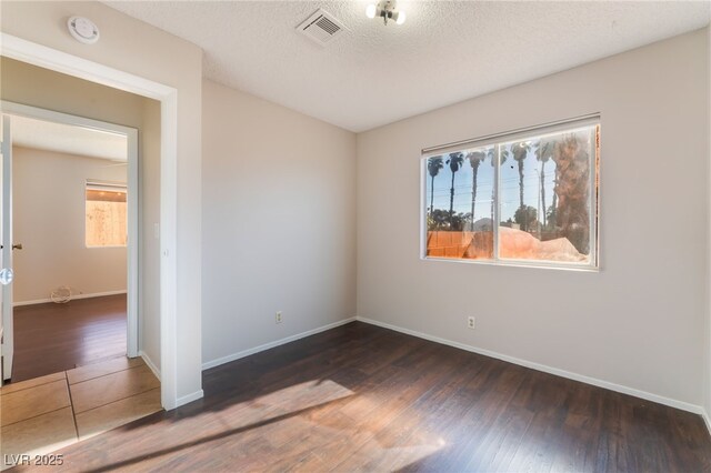 empty room featuring dark hardwood / wood-style floors and a textured ceiling