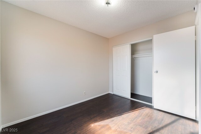 unfurnished bedroom with a textured ceiling, a closet, and dark hardwood / wood-style flooring