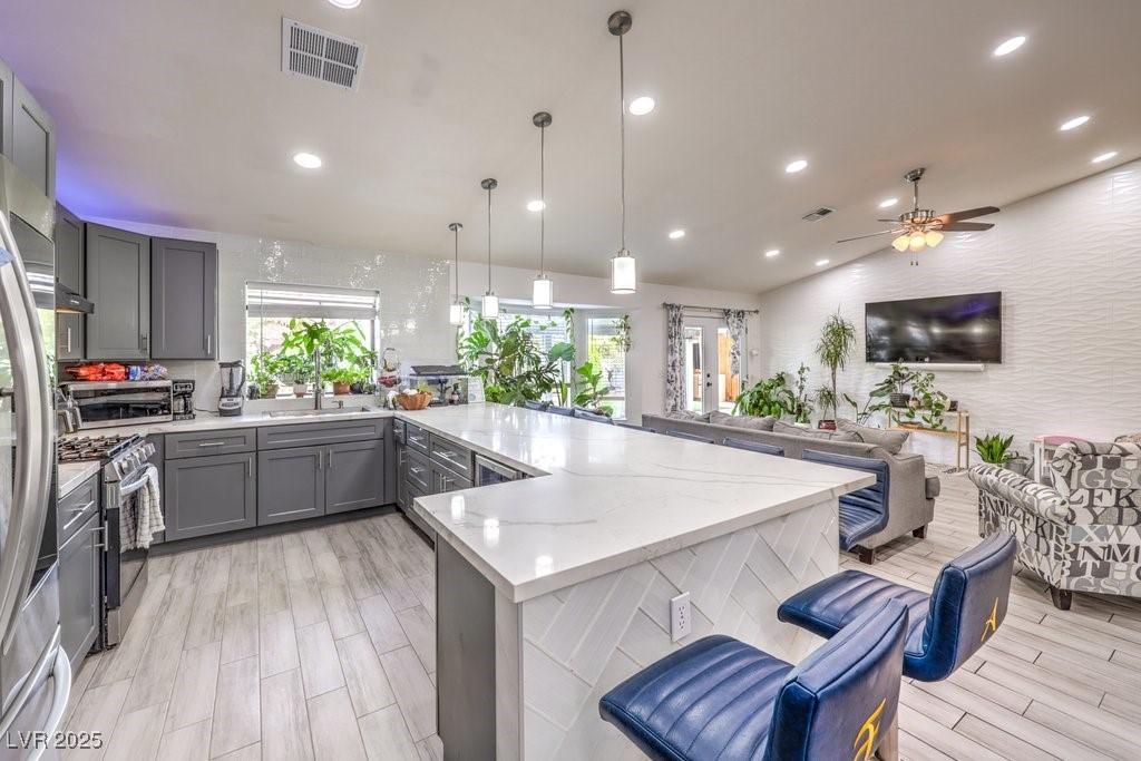 kitchen featuring gray cabinets, ceiling fan, appliances with stainless steel finishes, pendant lighting, and sink