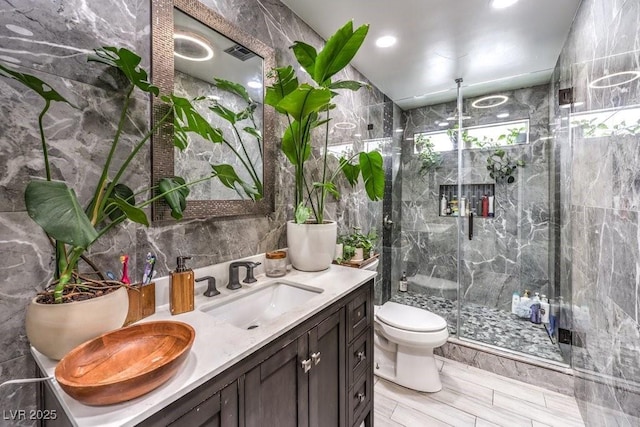 bathroom with vanity, toilet, tile walls, and an enclosed shower