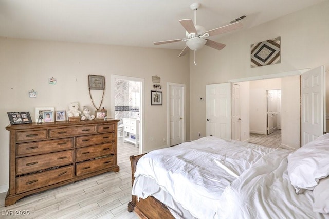 bedroom with ceiling fan, light hardwood / wood-style flooring, ensuite bath, and vaulted ceiling