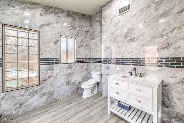 bathroom with tile walls, toilet, and vanity