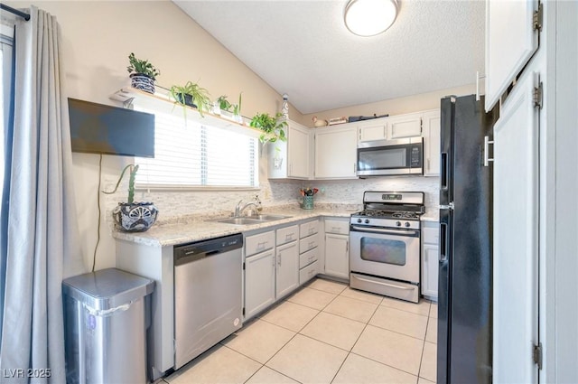 kitchen featuring vaulted ceiling, light tile patterned flooring, sink, backsplash, and stainless steel appliances