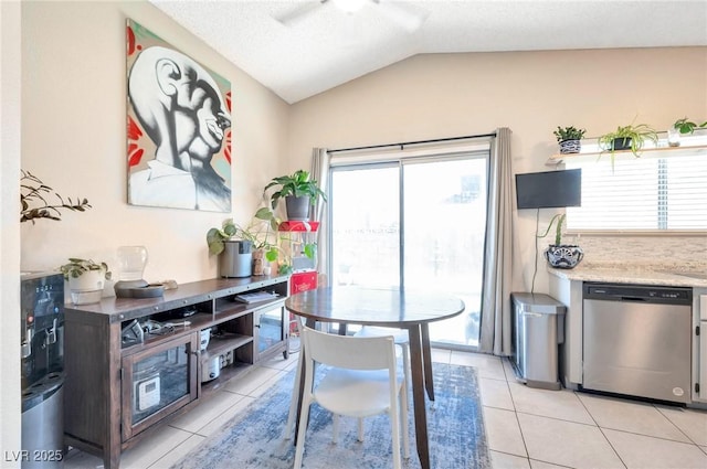 tiled dining room featuring ceiling fan, lofted ceiling, and a textured ceiling