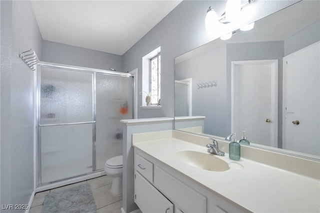 bathroom featuring walk in shower, vanity, toilet, and tile patterned flooring