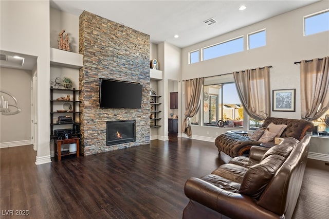 living room with built in shelves, a fireplace, dark hardwood / wood-style floors, and a high ceiling