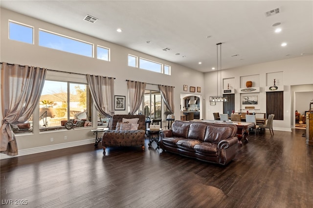 living room with a towering ceiling and dark hardwood / wood-style flooring