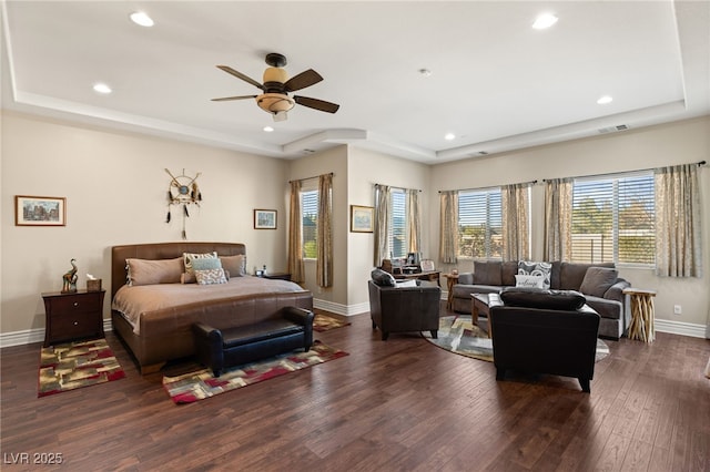 bedroom with dark hardwood / wood-style floors, a raised ceiling, and ceiling fan