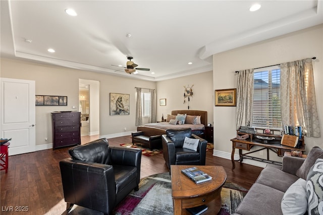 living room with a raised ceiling, ceiling fan, and dark hardwood / wood-style flooring