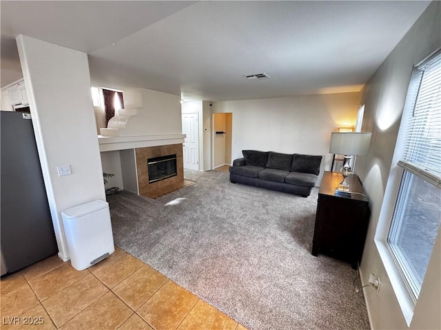 carpeted living room with a tile fireplace