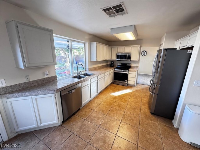 kitchen with light tile patterned floors, stainless steel appliances, sink, and white cabinets