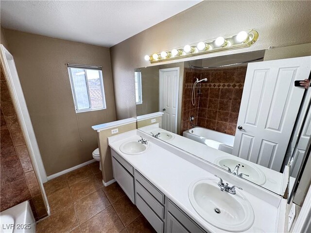 full bathroom featuring vanity, tiled shower / bath combo, tile patterned floors, and toilet