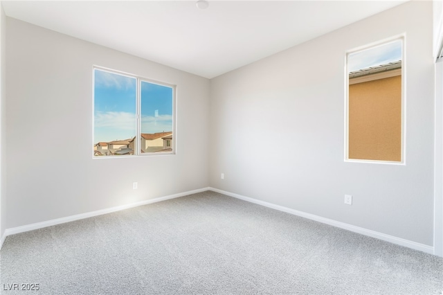 carpeted spare room featuring baseboards and a wealth of natural light