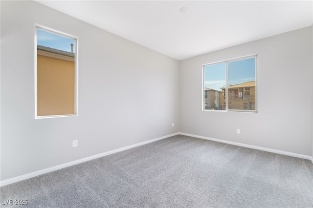 spare room featuring a wealth of natural light, baseboards, and carpet