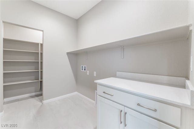 washroom featuring washer hookup, cabinet space, and baseboards