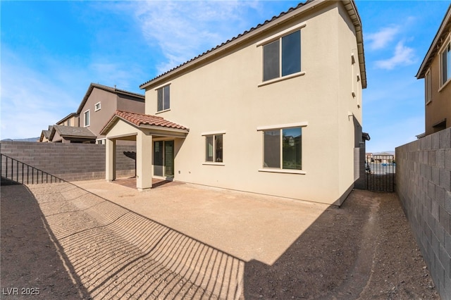 back of house with a tiled roof, stucco siding, a fenced backyard, and a patio area