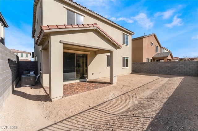 back of house with central AC unit, a fenced backyard, stucco siding, a tiled roof, and a patio area