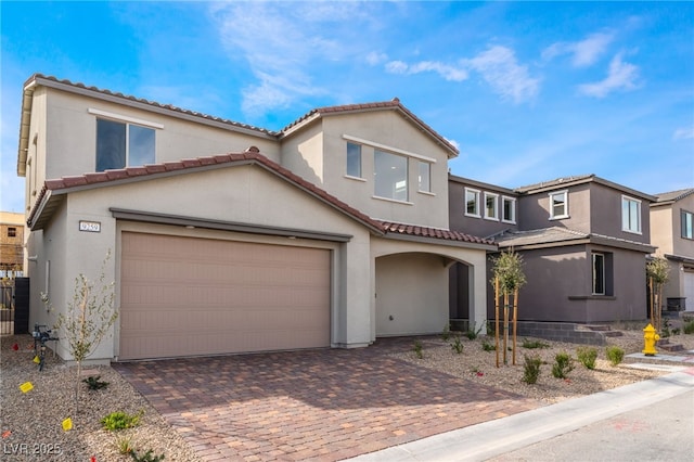 mediterranean / spanish home with a tile roof, decorative driveway, fence, and stucco siding