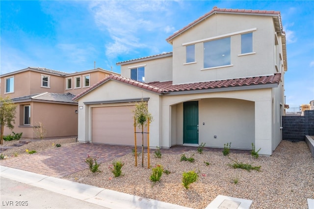 mediterranean / spanish-style house featuring stucco siding, decorative driveway, fence, an attached garage, and a tiled roof