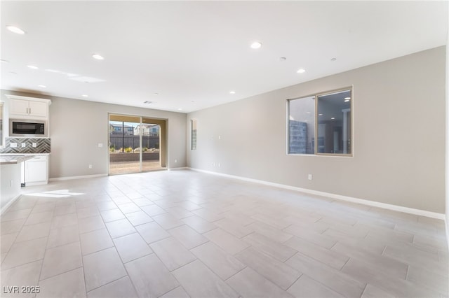 unfurnished living room featuring recessed lighting and baseboards