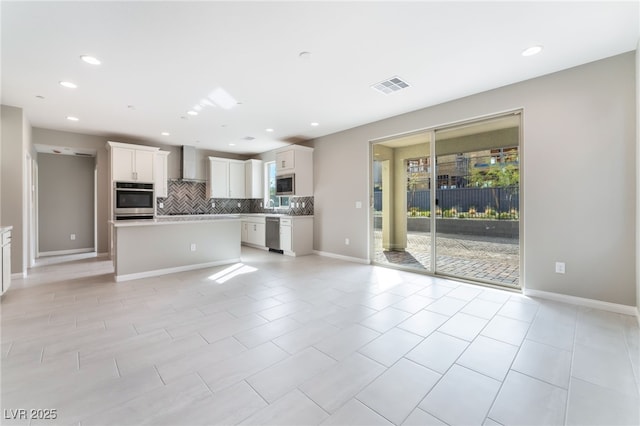 kitchen with visible vents, decorative backsplash, appliances with stainless steel finishes, wall chimney exhaust hood, and open floor plan