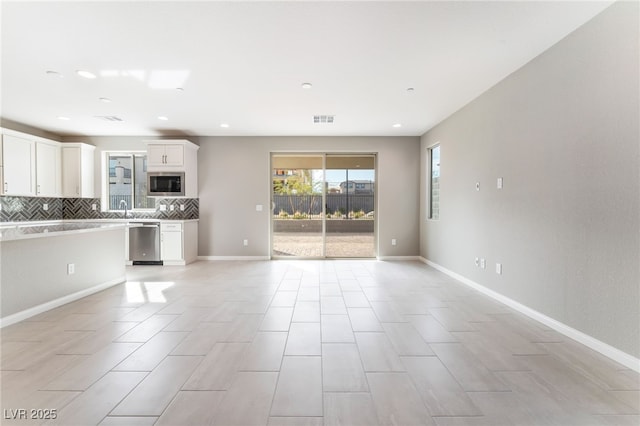 kitchen featuring tasteful backsplash, visible vents, open floor plan, appliances with stainless steel finishes, and white cabinets