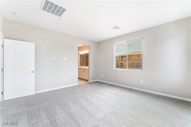 unfurnished bedroom with light carpet, visible vents, connected bathroom, and baseboards