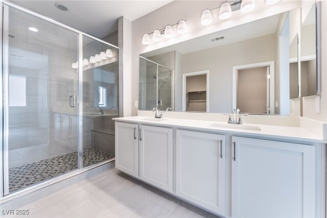 bathroom with double vanity, visible vents, a shower stall, and a sink