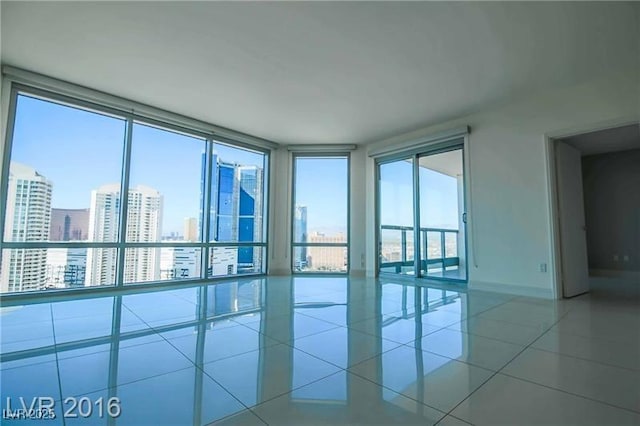 unfurnished room with a wealth of natural light, floor to ceiling windows, and light tile patterned flooring