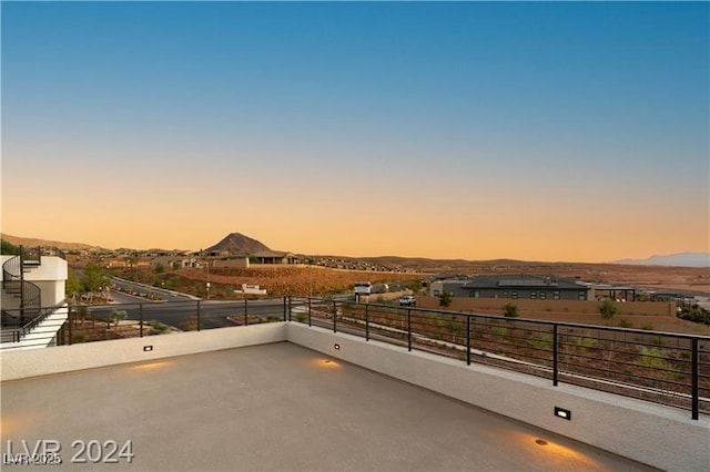 patio terrace at dusk with a mountain view and a balcony