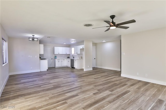 unfurnished living room featuring sink, ceiling fan with notable chandelier, and light hardwood / wood-style floors