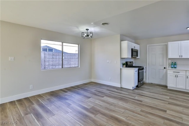 kitchen featuring an inviting chandelier, appliances with stainless steel finishes, light hardwood / wood-style flooring, and white cabinets