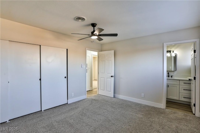 unfurnished bedroom with ensuite bath, light carpet, sink, a closet, and ceiling fan