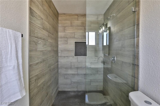 bathroom with toilet and a tile shower