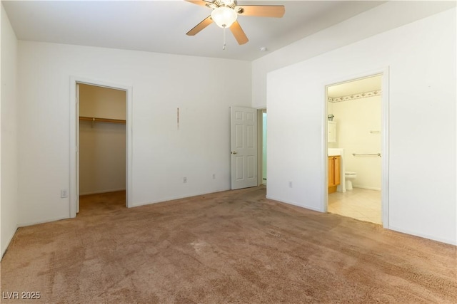 unfurnished bedroom featuring light carpet, ceiling fan, connected bathroom, a closet, and a walk in closet