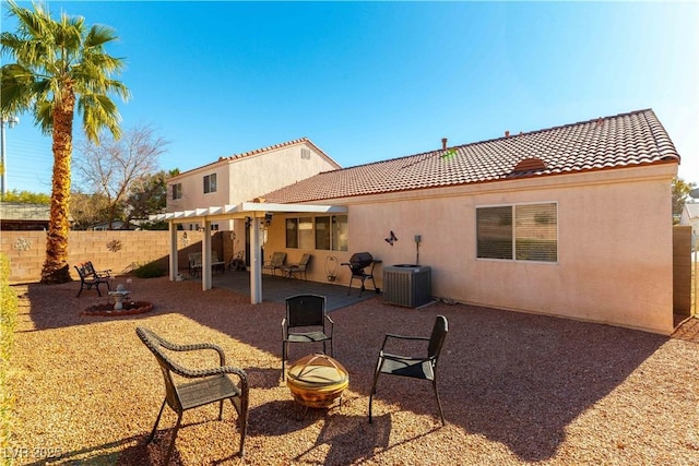 rear view of property with central air condition unit, a pergola, a patio area, and a fire pit