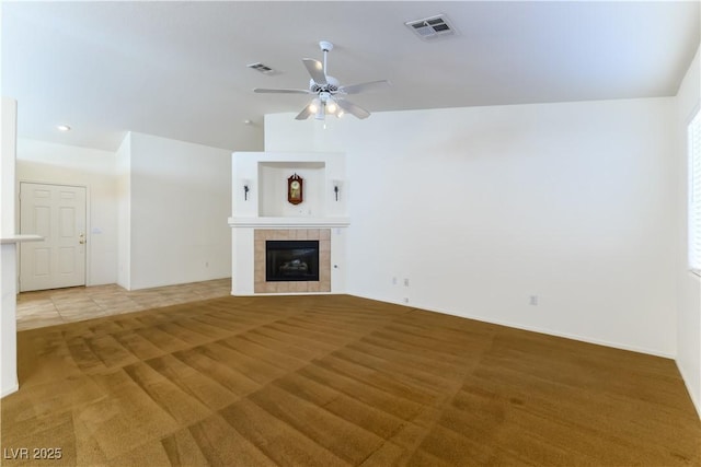 unfurnished living room featuring ceiling fan, carpet floors, and a tile fireplace