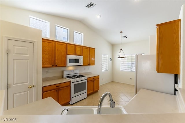 kitchen featuring decorative light fixtures, white appliances, light tile patterned flooring, lofted ceiling, and sink