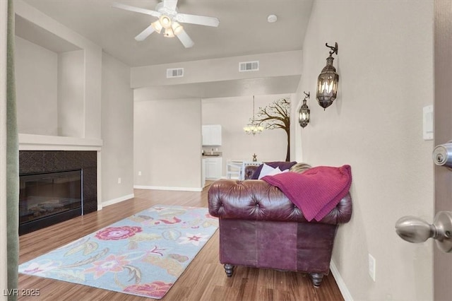 living room featuring ceiling fan, hardwood / wood-style floors, and a fireplace