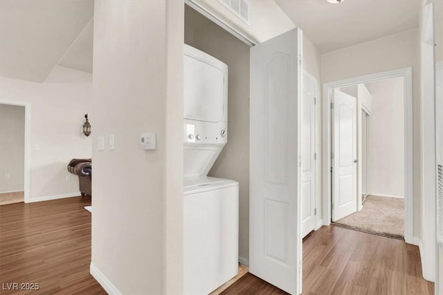 clothes washing area with stacked washer and dryer and dark hardwood / wood-style flooring