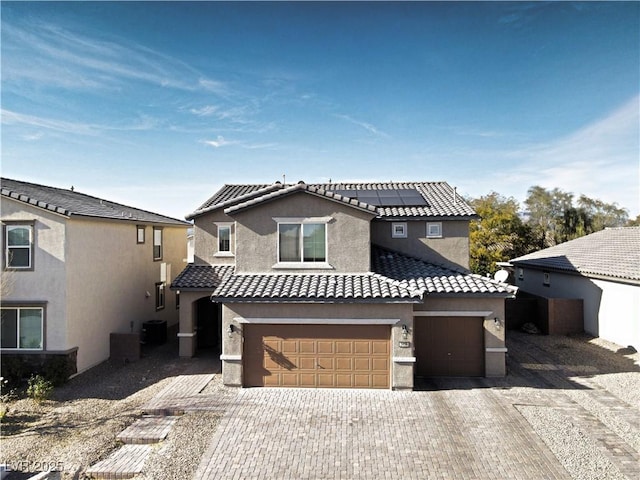 view of front facade with a garage, solar panels, and central AC