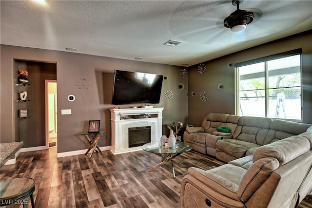 living room featuring ceiling fan, a textured ceiling, and dark hardwood / wood-style floors