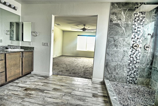 bathroom with ceiling fan, vanity, and a tile shower