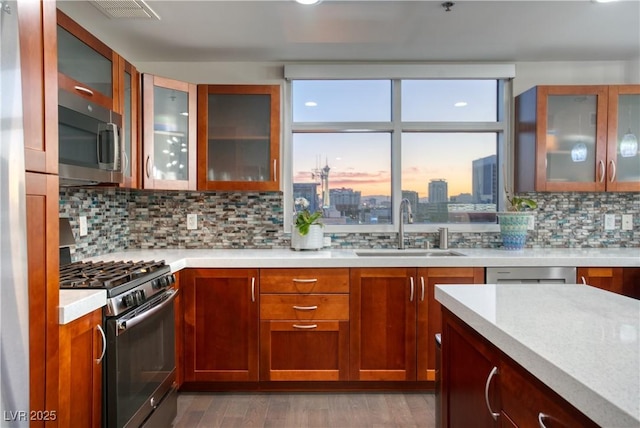 kitchen with decorative backsplash, sink, stainless steel appliances, and light wood-type flooring